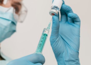 Profissional de saúde prepara seringa com vacina.