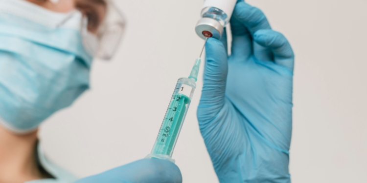Profissional de saúde prepara seringa com vacina.