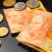 Cédulas de 20 reais e moedas brasileiras sobre mesa escura.
