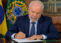 Imagem ilustrativa do presidente da República assinando documento no gabinete, ao lado da bandeira nacional, em referência ao anúncio sobre o fim da taxa das blusinhas nas compras internacionais