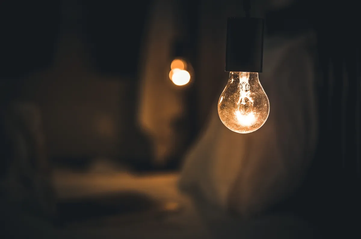 Lâmpada acesa em ambiente escuro representando o sistema de bandeiras tarifárias de energia elétrica
