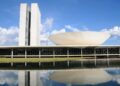 Vista do Congresso Nacional refletido no espelho d'água, em imagem ligada à tramitação do projeto sobre programas de fidelidade aéreos.