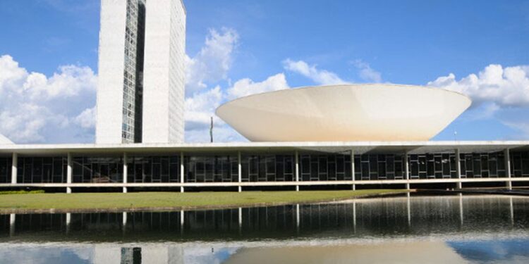Vista do Congresso Nacional refletido no espelho d'água, em imagem ligada à tramitação do projeto sobre programas de fidelidade aéreos.