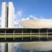Vista do Congresso Nacional refletido no espelho d'água, em imagem ligada à tramitação do projeto sobre programas de fidelidade aéreos.