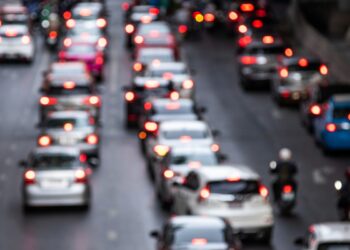 Imagem ilustrativa de trânsito congestionado em avenida, com fileiras de veículos e luzes de freio acesas ao entardecer, tema da matéria sobre as novas regras da Lei Seca aprovadas pelo Contran.