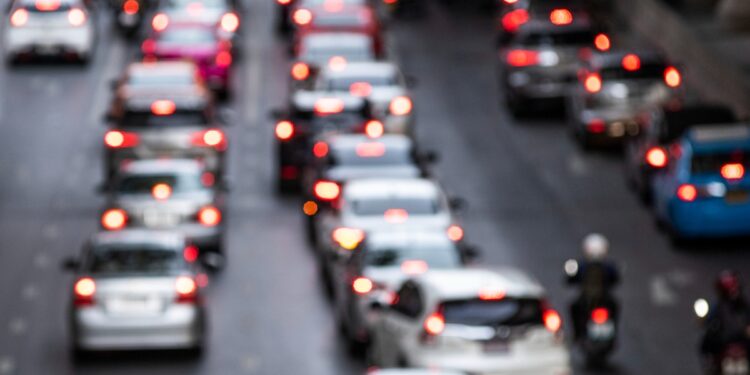 Imagem ilustrativa de trânsito congestionado em avenida, com fileiras de veículos e luzes de freio acesas ao entardecer, tema da matéria sobre as novas regras da Lei Seca aprovadas pelo Contran.