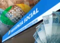 Arte com a marca do INSS sobre montagem da placa do edifício sede da Previdência Social e cédulas de cem reais, em referência à liberação do pagamento de agosto