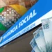Arte com a marca do INSS sobre montagem da placa do edifício sede da Previdência Social e cédulas de cem reais, em referência à liberação do pagamento de agosto