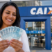 Imagem ilustrativa de mulher sorridente segurando várias cédulas de cem reais em leque diante da fachada de uma agência da Caixa, referência à liberação do saque para os aniversariantes do mês
