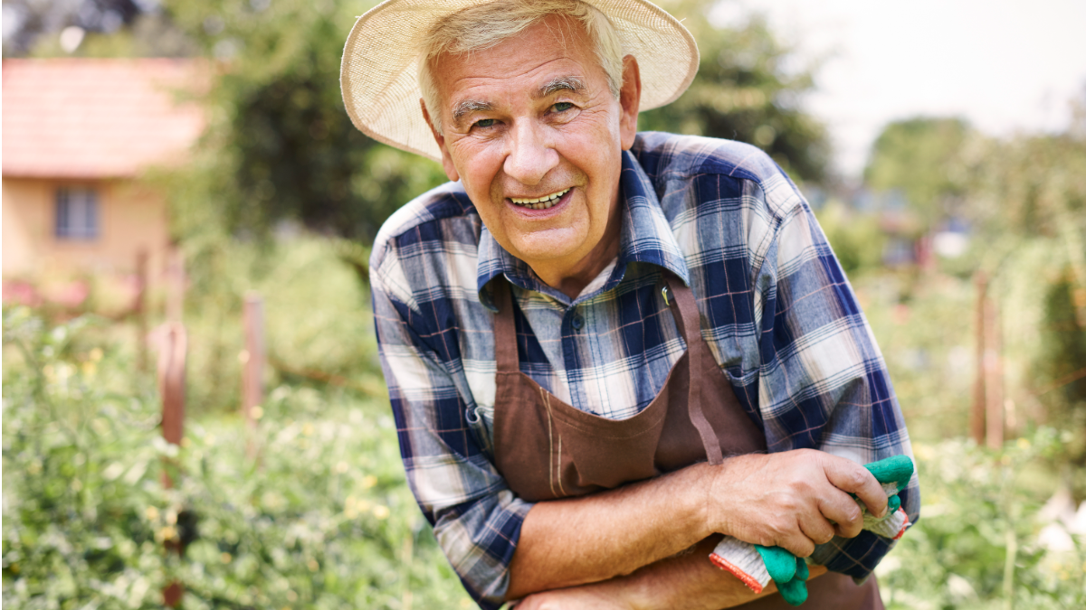 Homem sorridente trabalhando em horta no campo.