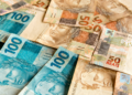 Notas de 50 e 100 reais espalhadas.