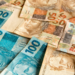 Notas de 50 e 100 reais espalhadas.