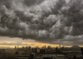 Nuvens de tempestade densas avançam sobre cidade ao entardecer.