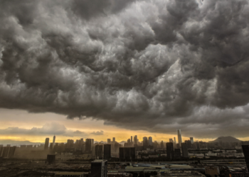 Nuvens de tempestade densas avançam sobre cidade ao entardecer.