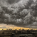 Nuvens de tempestade densas avançam sobre cidade ao entardecer.