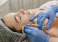 Aplicação de botox facial em clínica estética por profissional com luvas azuis.
