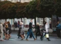 Pessoas atravessam rua movimentada indo ao trabalho em centro urbano.