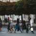 Pessoas atravessam rua movimentada indo ao trabalho em centro urbano.