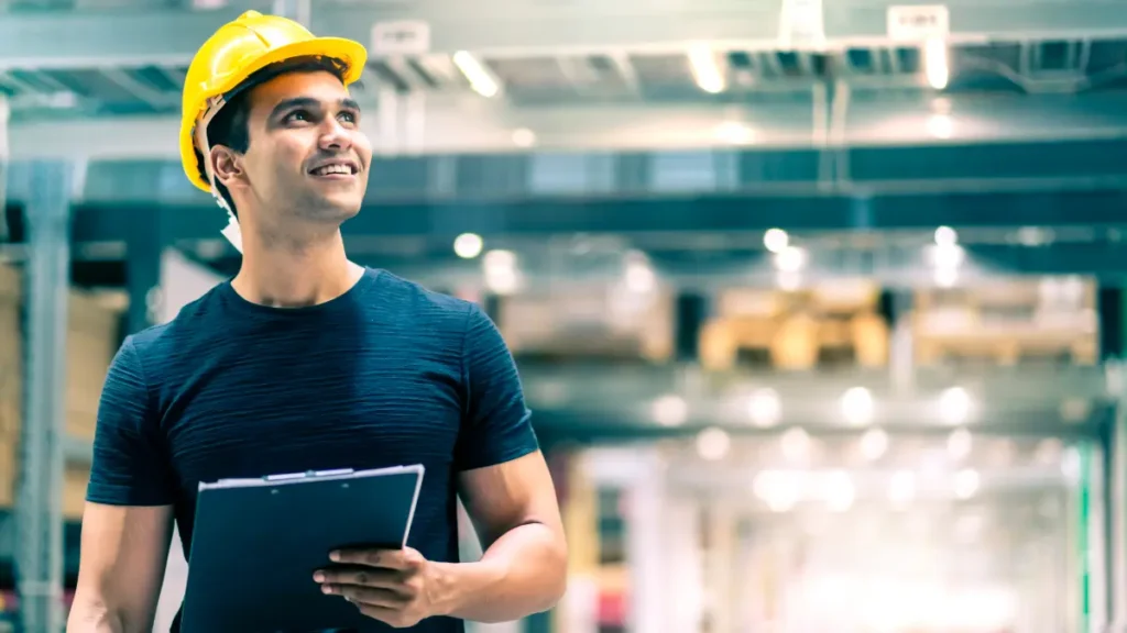 Jovem operário confiante avaliando ambiente industrial moderno.