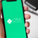 Mão segura smartphone com tela verde do Pix, próximo a máquina de cartão de crédito.