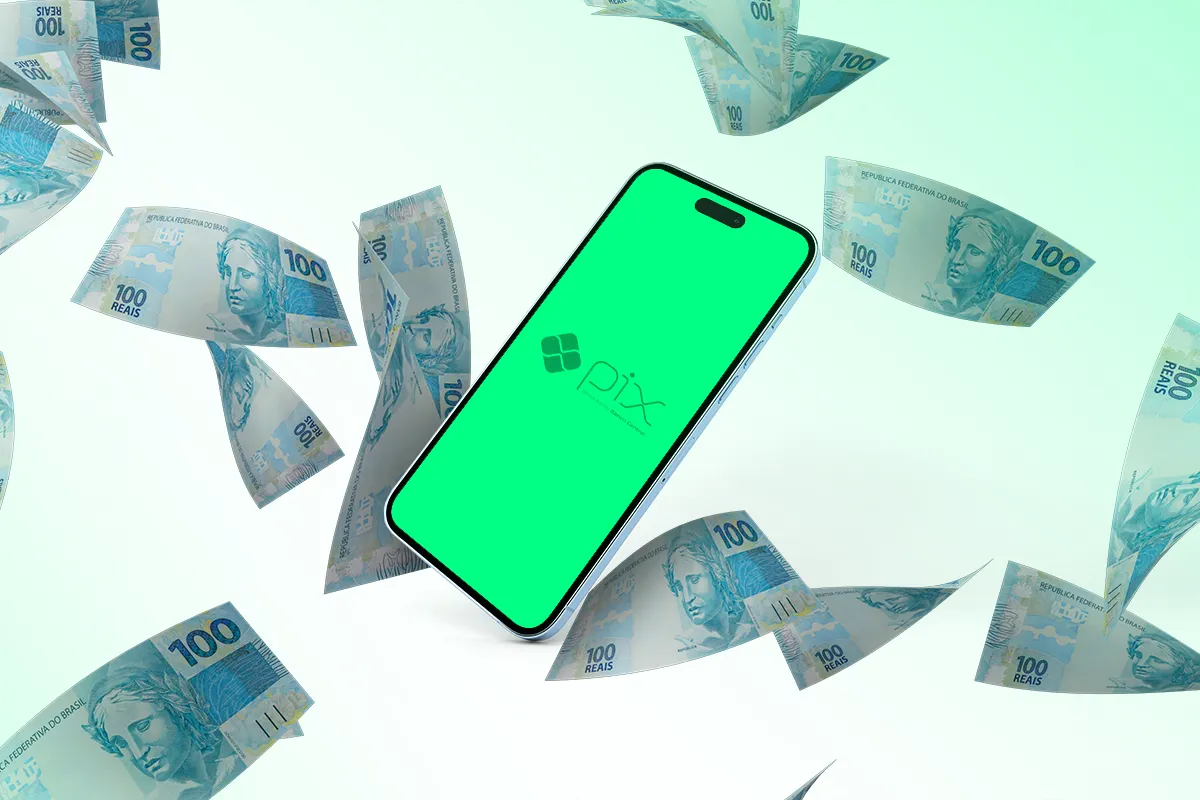 Celular exibindo tela do Pix cercado por diversas notas de 100 reais flutuando.