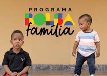 Dois meninos pequenos, um sentado e outro em pé, com logo do Bolsa Família ao fundo.