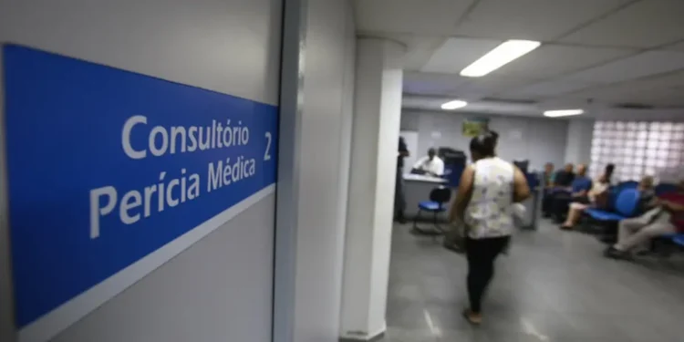 Sinalização "Consultório Perícia Médica 2" e pessoas aguardando em sala de espera ampla.
