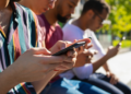 Jovens conectados utilizando smartphones em ambiente urbano.