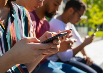 Jovens conectados utilizando smartphones em ambiente urbano.
