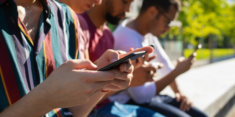 Jovens conectados utilizando smartphones em ambiente urbano.