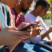 Jovens conectados utilizando smartphones em ambiente urbano.