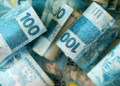 Notas de cem reais brasileiras em destaque sobrepostas.