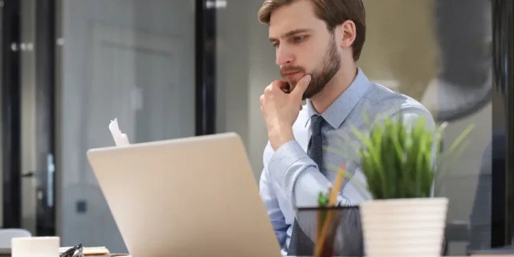 Homem olhando atento para notebook.
