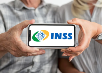 Duas pessoas seguram celular exibindo logo do INSS, foco nas mãos e aparelho.