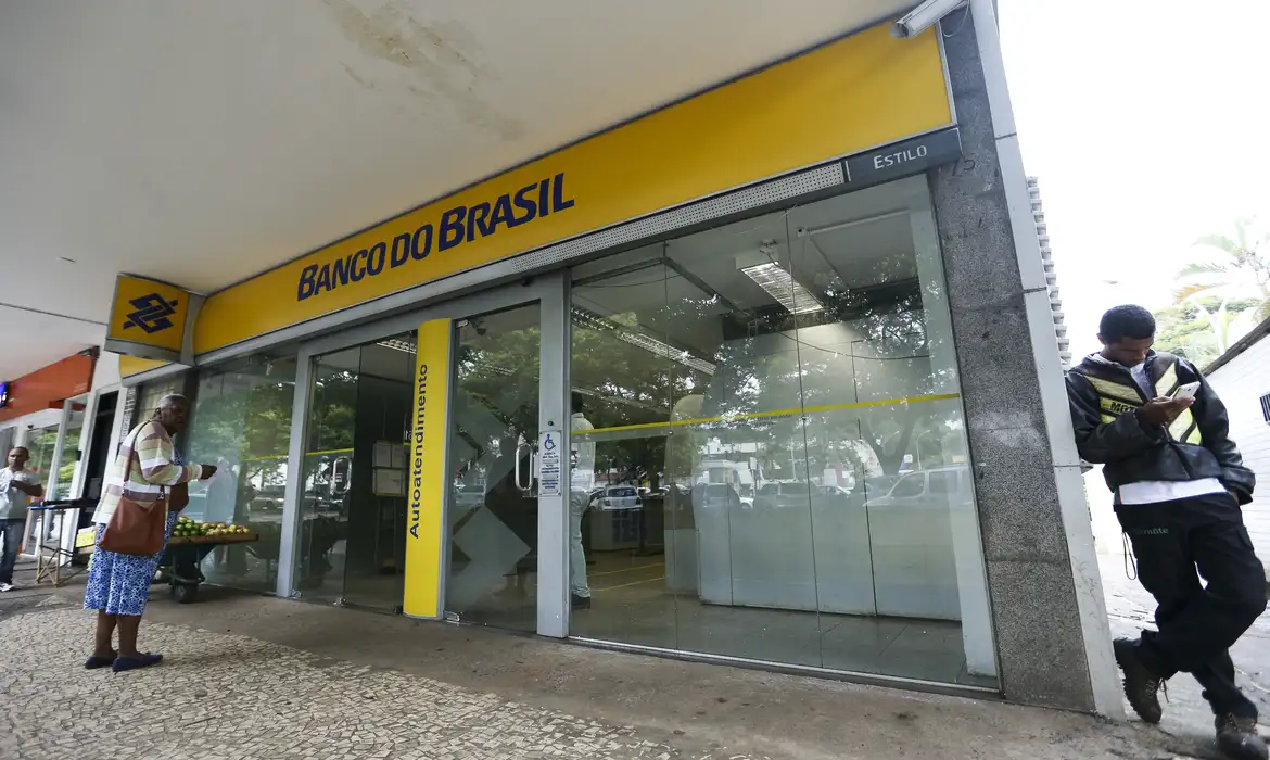 Fachada do Banco do Brasil em cidade brasileira com pessoas na calçada.