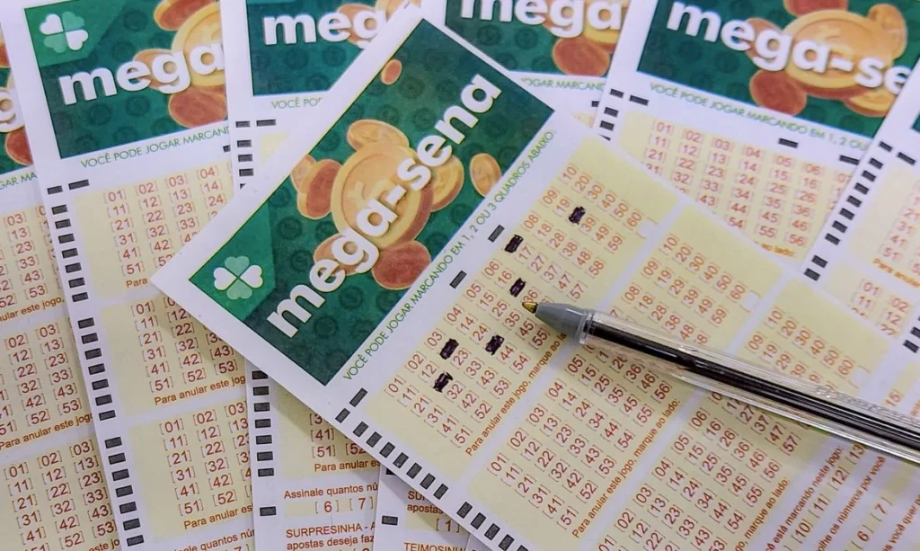 Volantes da Mega-Sena com números marcados e caneta sobre uma das apostas
