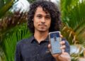 Jovem mostra a tela do celular com o e-Título, documento digital do eleitor, em meio a folhagens