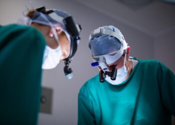 Imagem ilustrativa: cirurgiões com lupas em centro cirúrgico, em referência à cirurgia de catarata e glaucoma pelo SUS