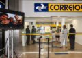 Clientes e funcionários dentro de uma agência dos Correios, com o letreiro da estatal acima dos guichês de atendimento.