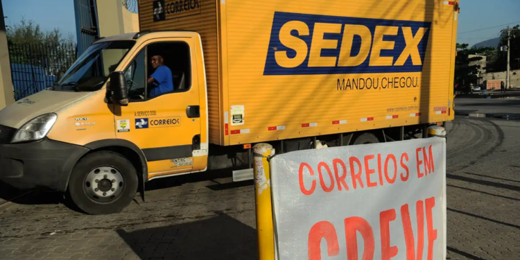 Imagem ilustrativa: caminhão amarelo do Sedex atrás de uma faixa com os dizeres Correios em greve, cena que remete ao impacto da greve dos Correios nas entregas da Shein