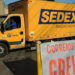 Imagem ilustrativa: caminhão amarelo do Sedex atrás de uma faixa com os dizeres Correios em greve, cena que remete ao impacto da greve dos Correios nas entregas da Shein
