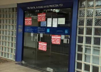 Entrada de agência da Caixa Econômica Federal com cartazes informando sobre greve dos bancários.