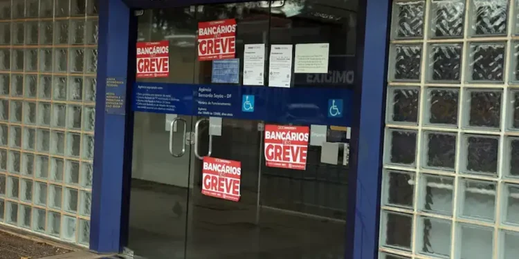 Entrada de agência da Caixa Econômica Federal com cartazes informando sobre greve dos bancários.