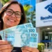 Contribuinte segura cédulas de reais em frente à Receita Federal, representando a liberação do lote residual de restituição do Imposto de Renda 2026.