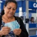 Beneficiária confere notas de R$ 100 em agência bancária, representando o pagamento do BPC.