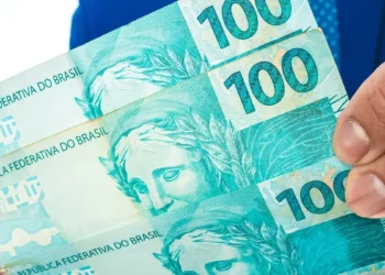 Mão segurando notas de real representa o valor disponível para retirada pelo saque-aniversário do FGTS.