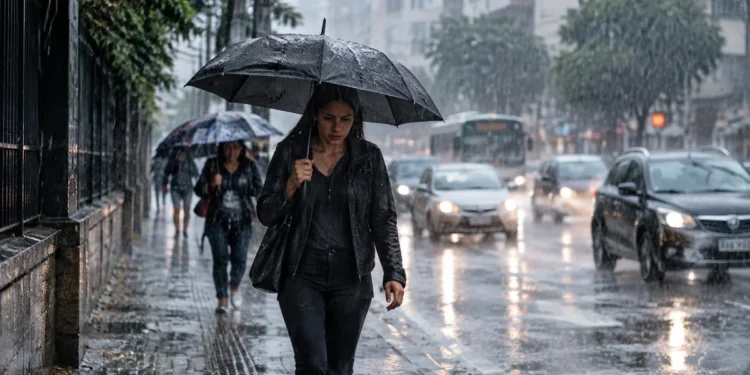Pessoa caminhando com guarda-chuva durante chuva intensa em área urbana, representando a previsão de chuvas no Sul e Sudeste