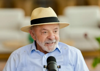 Presidente Luiz Inácio Lula da Silva, de chapéu de palha e camisa azul, fala ao microfone durante anúncio do reajuste no Bolsa Família