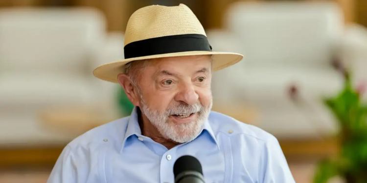 Presidente Luiz Inácio Lula da Silva, de chapéu de palha e camisa azul, fala ao microfone durante anúncio do reajuste no Bolsa Família