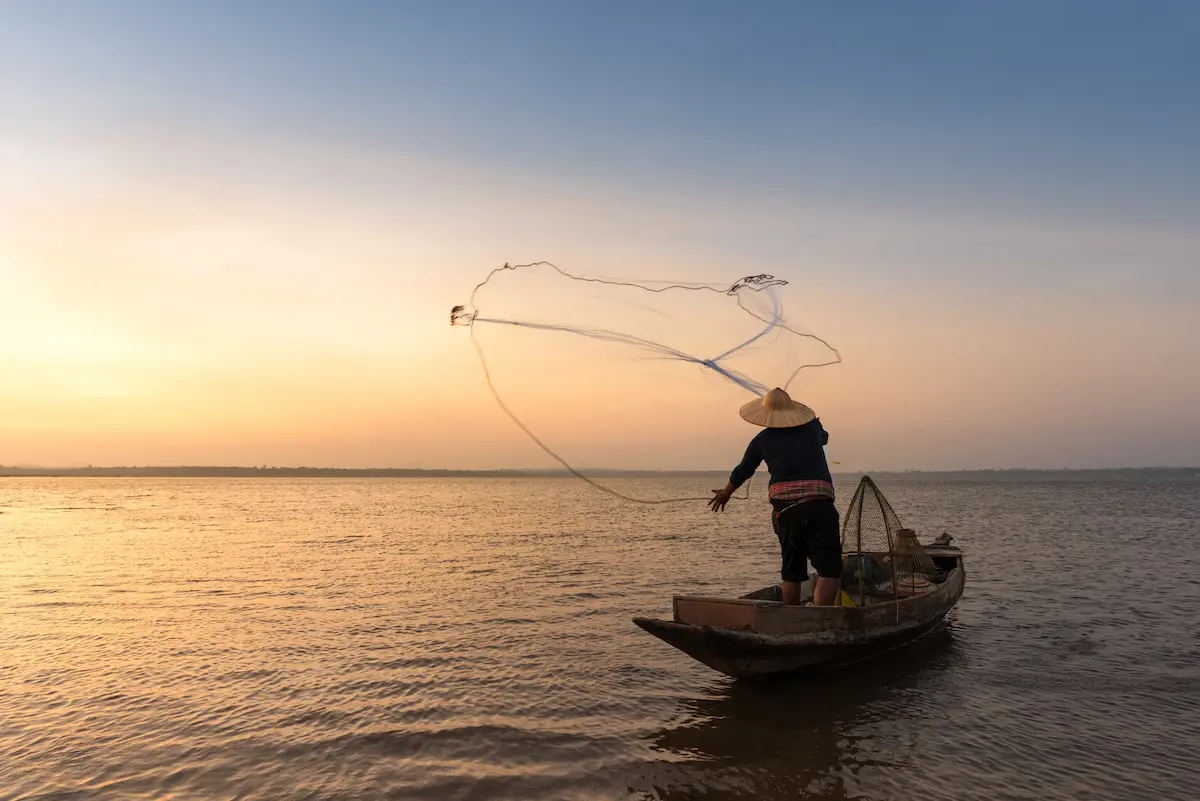 Pescador artesanal em barco durante atividade de pesca, representando pagamento do seguro defeso pelo INSS.